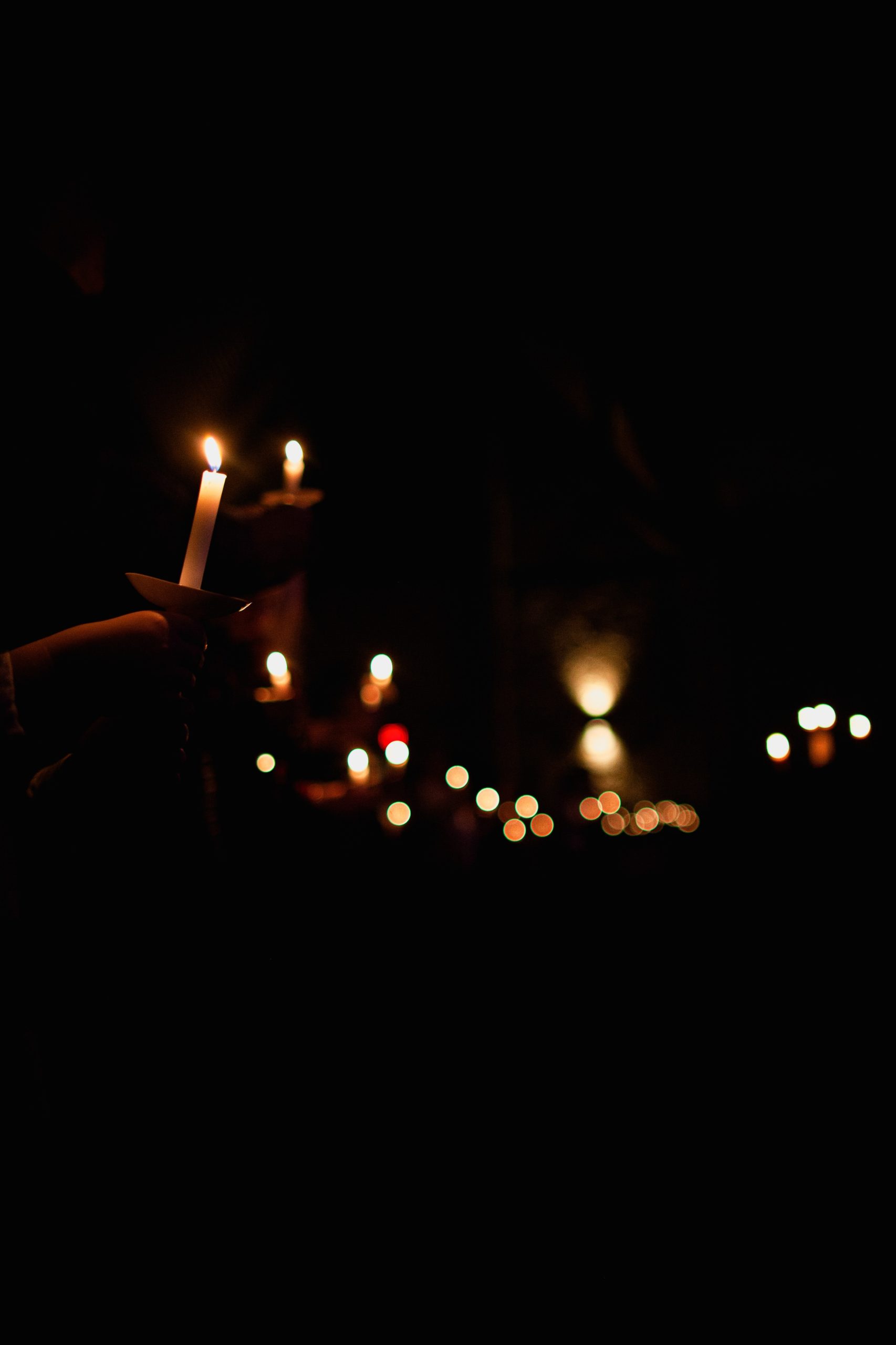 Hands hold candles in a dark room